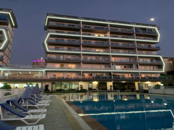 Exodus Residence Alanya Mahmutlar – modernes Wohngebäude mit Poolbeleuchtung bei Nacht