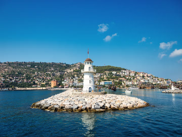 Panoramablick auf Alanya im Winter mit Hafen, Kızılkule, Festungsmauern und dem Mittelmeer unter blauem Himmel.