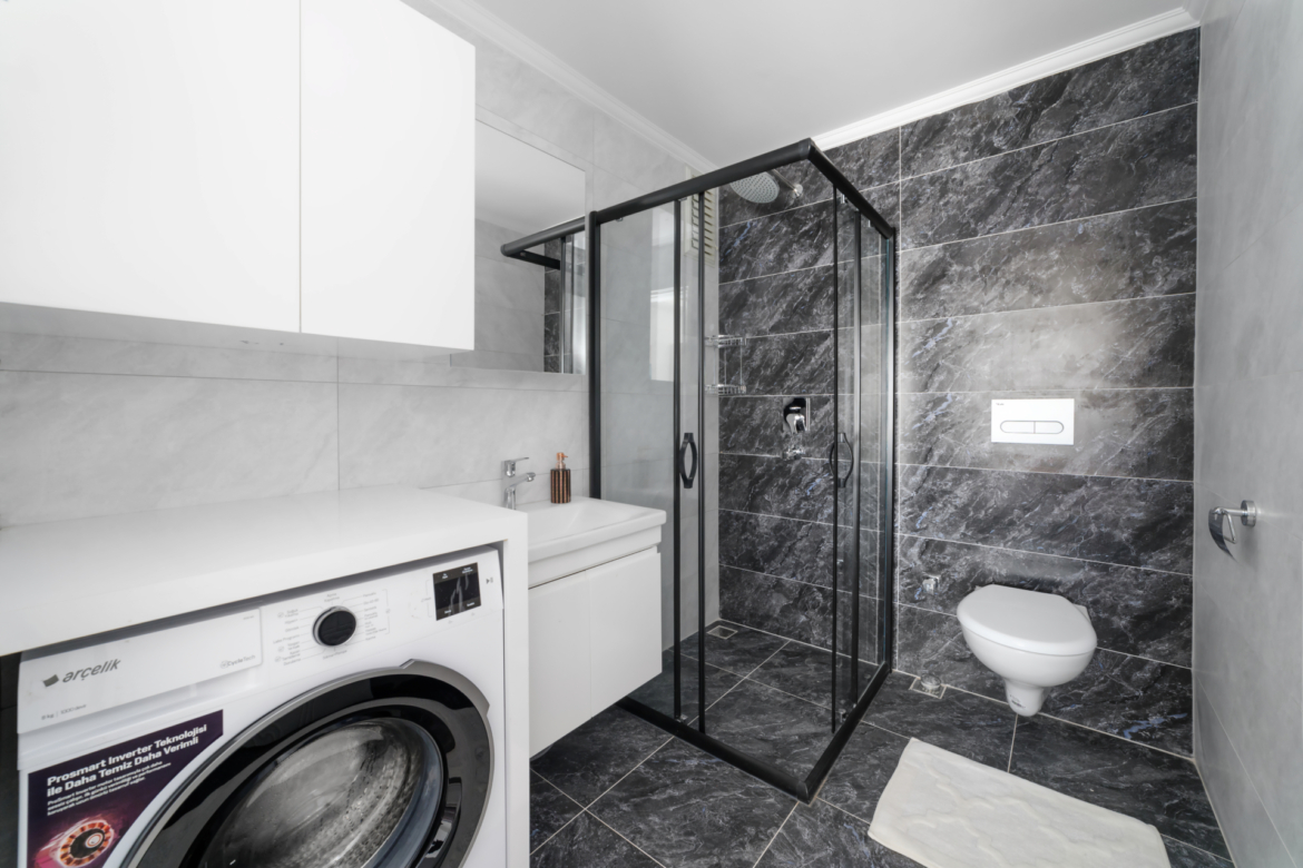 Modern bathroom with shower, washing machine and high-quality tiles in an apartment in Mahmutlar